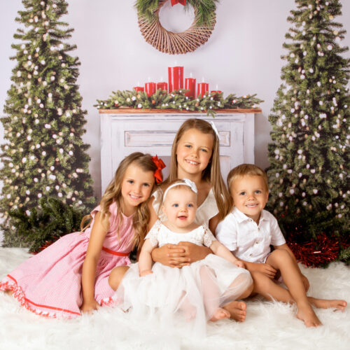 brother and sisters family photo with Christmas trees and fireplace