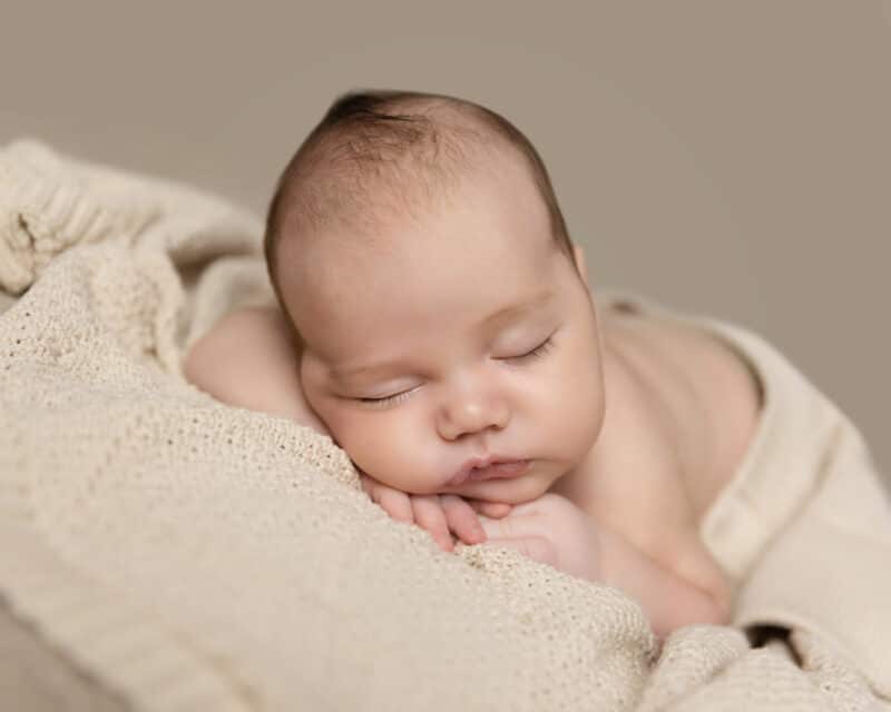 newborn baby sleeping with cream wrap