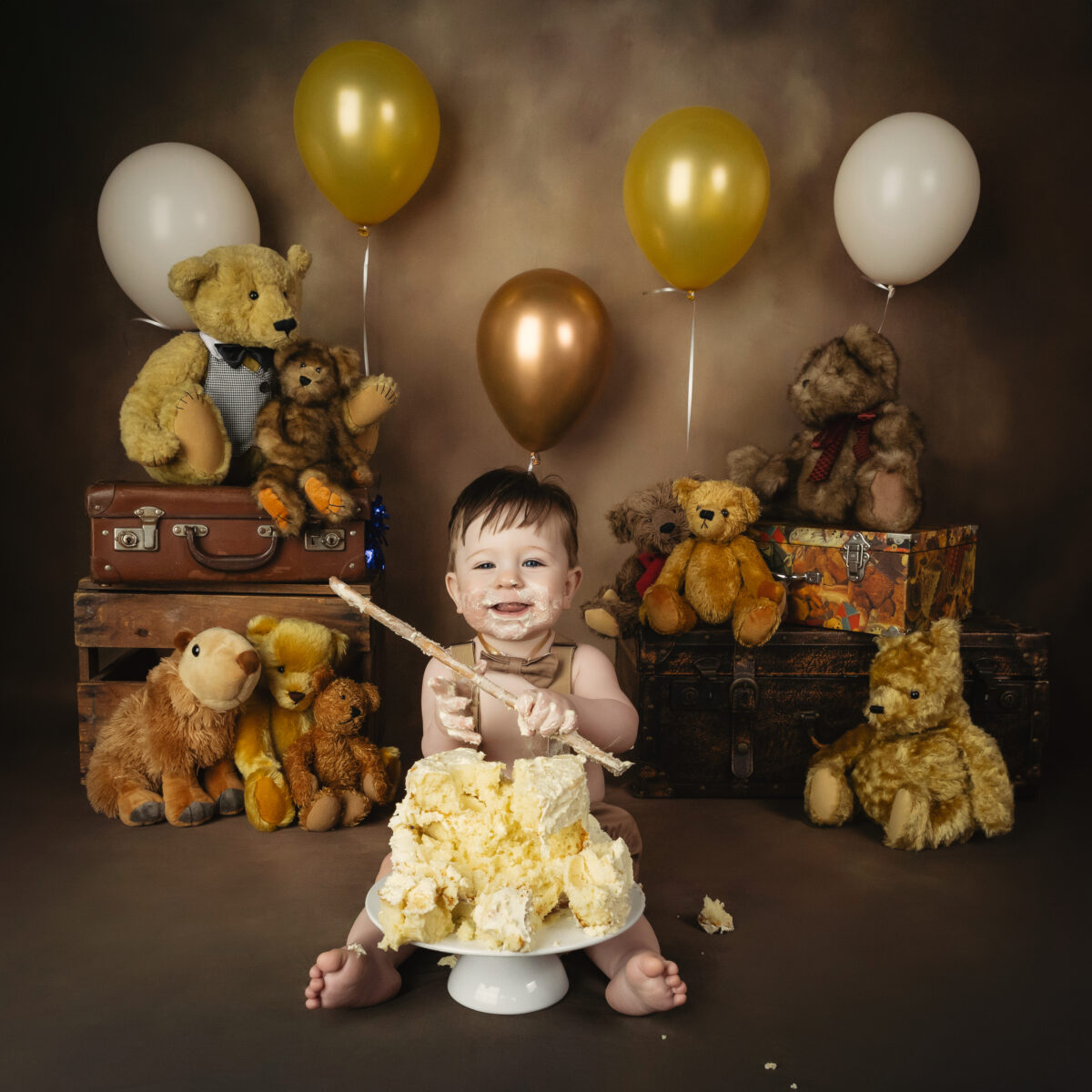 boy in brown overalls holding wooden spoon with teddy bears eating cake