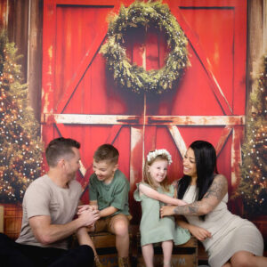 family Christmas photo tickling with Christmas wreath and Christmas trees