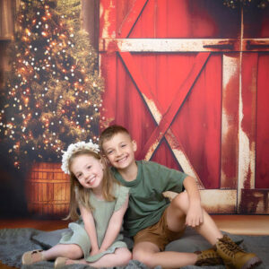 brother and sister Christmas photo with Christmas wreath and Christmas trees