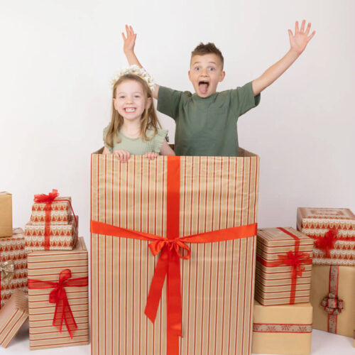 siblings boy and girl popping out of present christmas photo