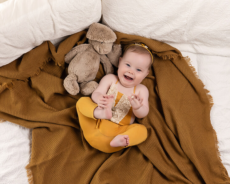 Baby laying on her back grabbing feet - studio photography - mustards and whites 2