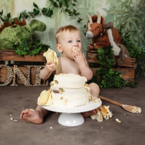 baby smashing and eating birthday cake with dinosaurs
