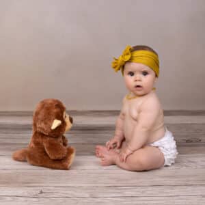 baby in yellow scarf and necklace with teddy bear photography