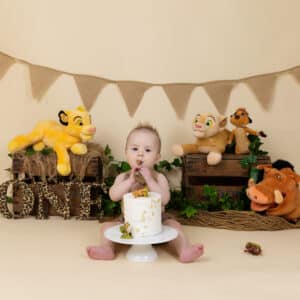 baby with birthday cake and lion king back drop